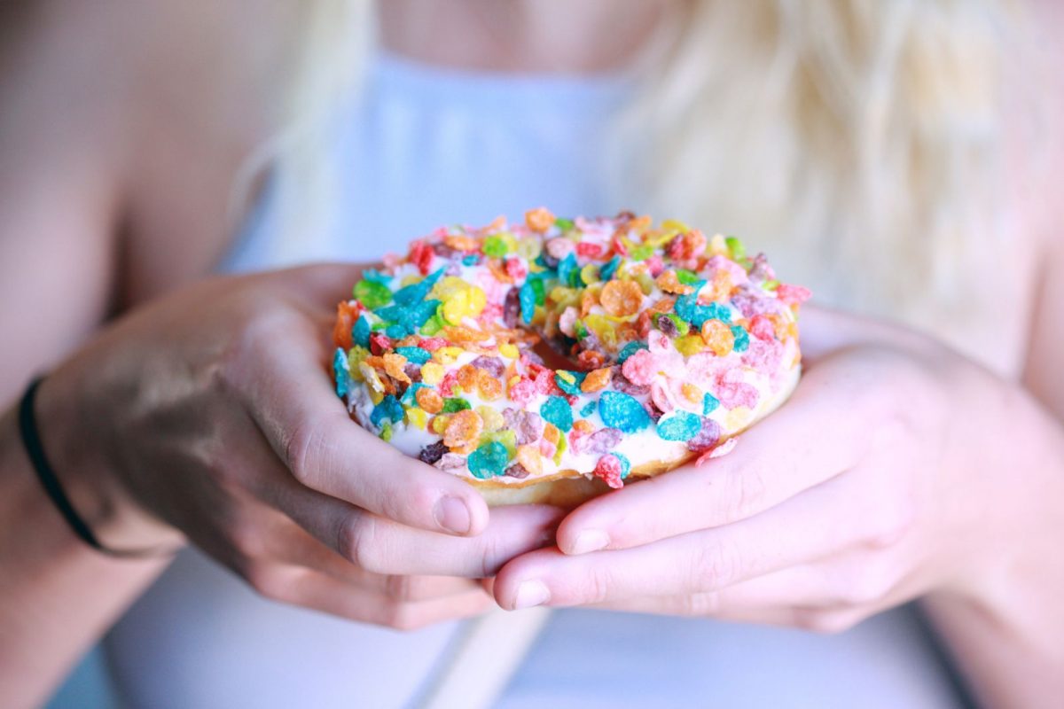An iced doughnut with Fruity Pebbles cereal as sprinkles