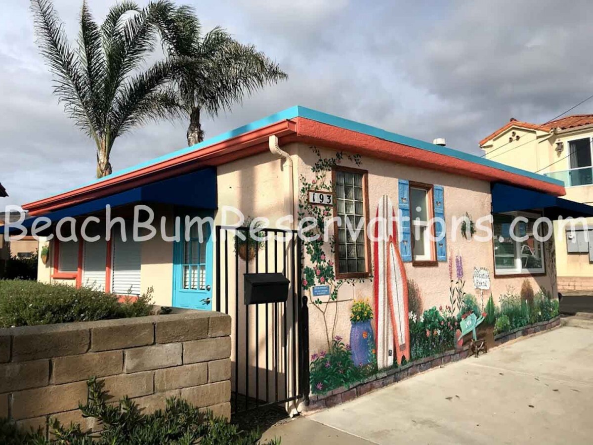 Exterior of small tan home with blue and red accents.